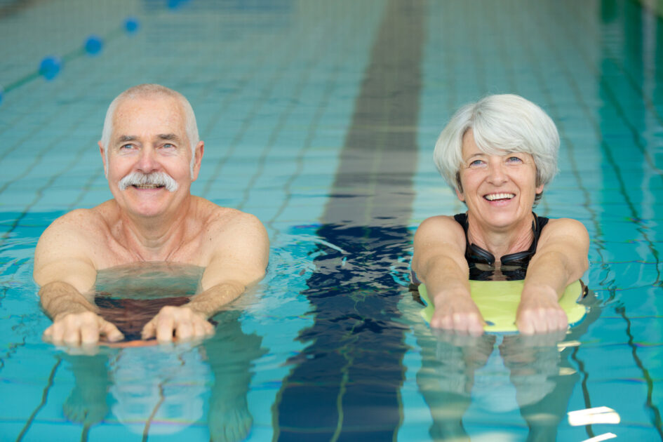 Ein älteres Ehepaar macht Schwimmübungen im Pool