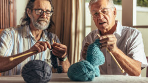 Zwei ältere Herren, die zu Hause stricken