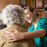 Freundliche Krankenschwester hilft älteren Dame bei Aktivitäten