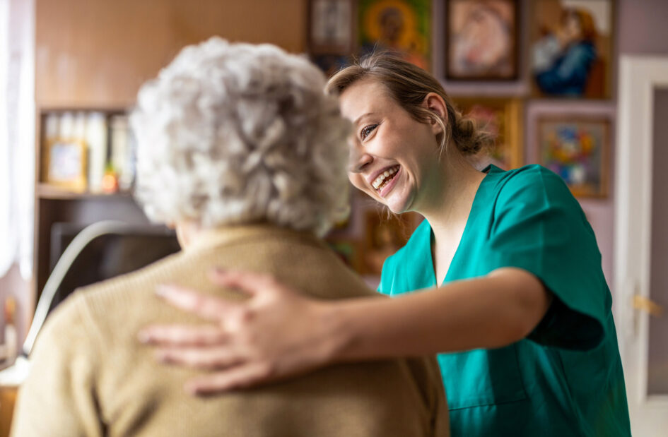 Freundliche Krankenschwester hilft älteren Dame bei Aktivitäten