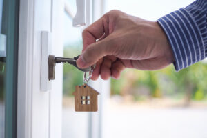 Hand entriegelt mit Hausschlüssel die Tür zum neuen Zuhause